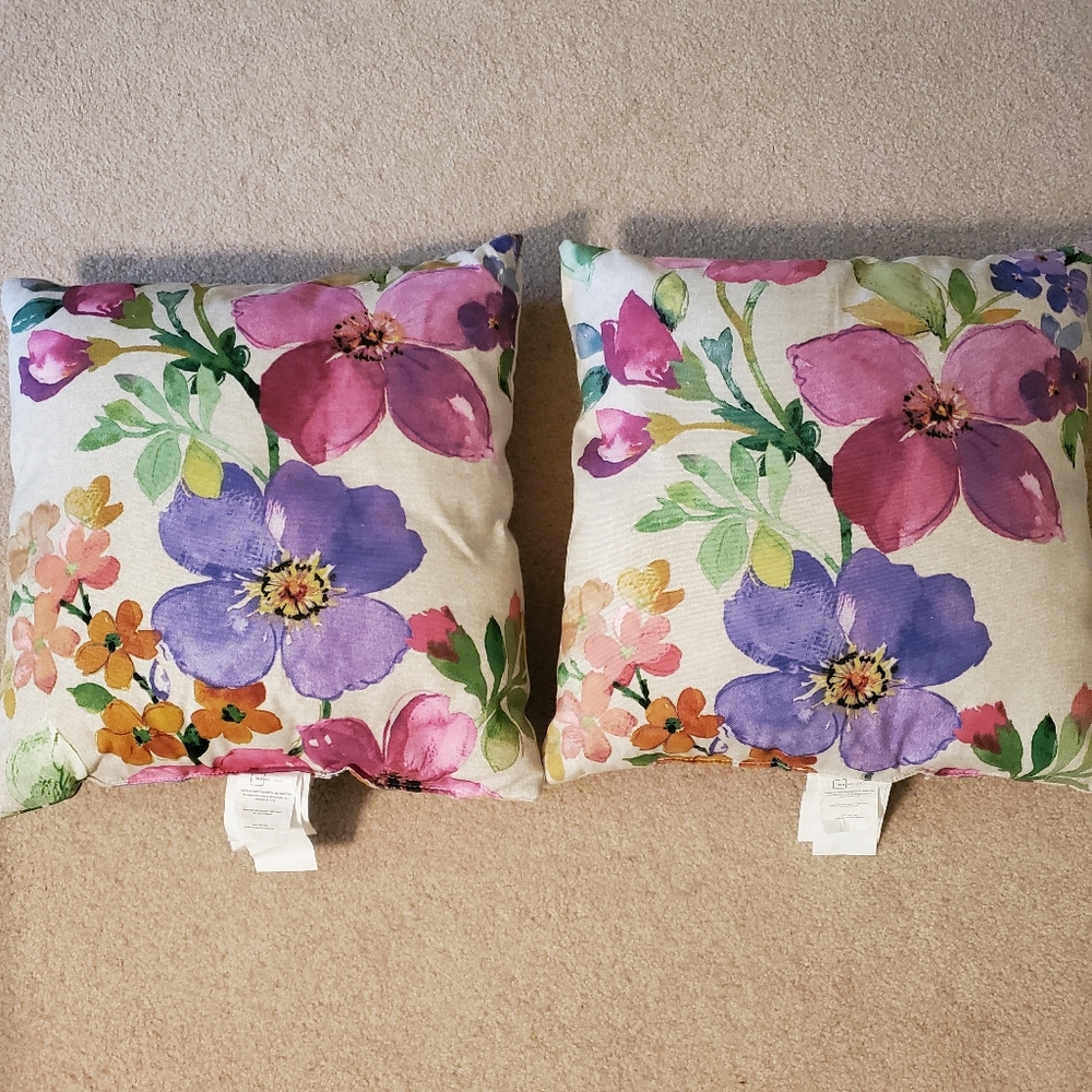 Two pink/purple flower throw pillows, sold as a pair.